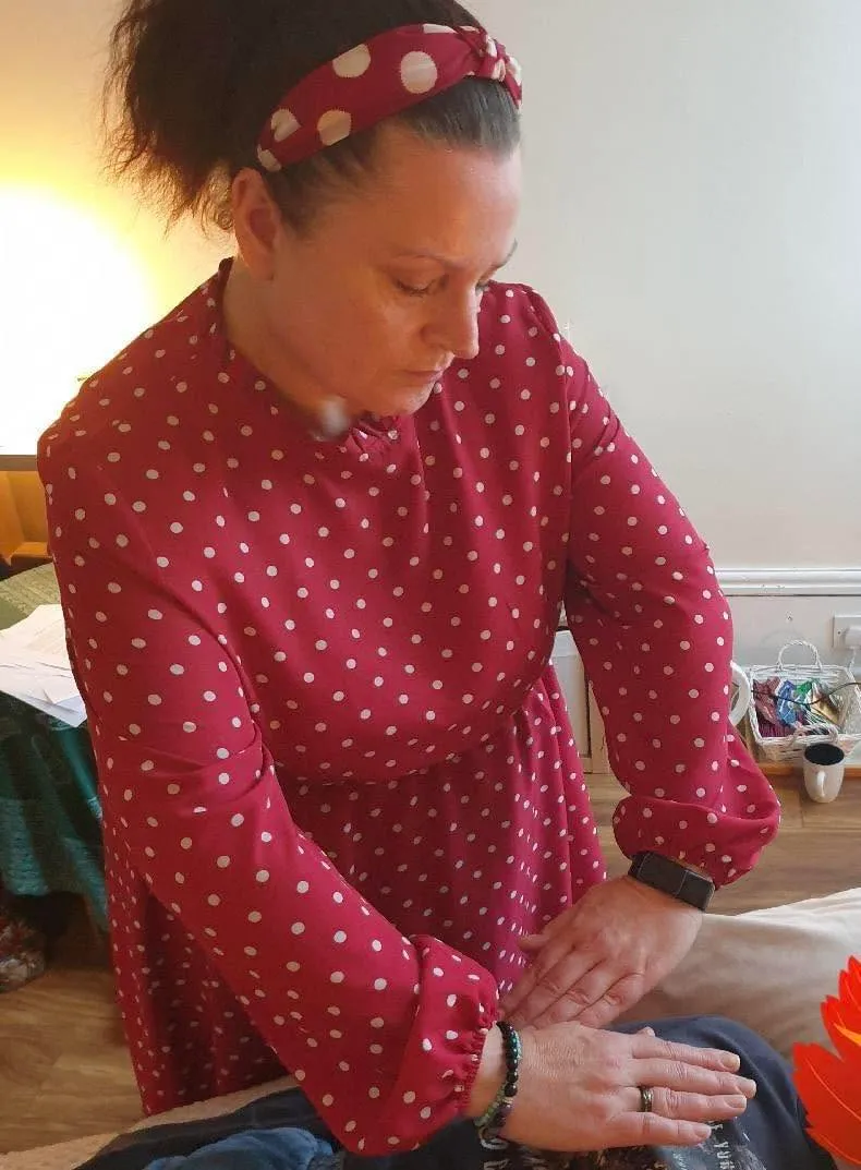 Alex, the practitioner behind SpiritSpud, giving a treatment in her red polka-dot top