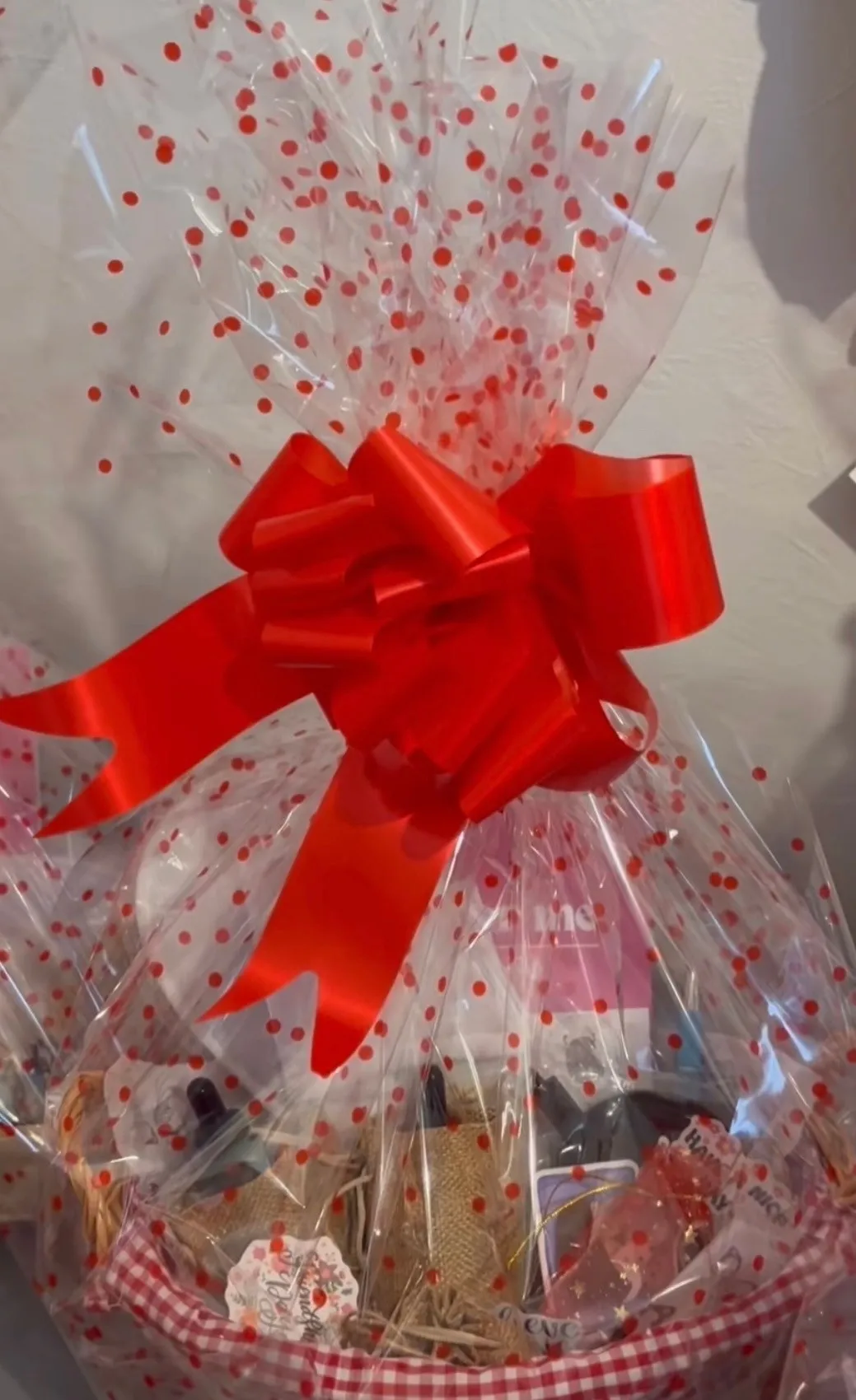 A SpiritSpud wellness pamper hamper: a wicker basket lined with red gingham, filled with goodies and wrapped in polka-dot cellophane with a big red bow